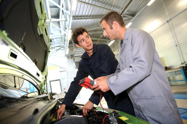 Trainer with student in repairshop checking on battery